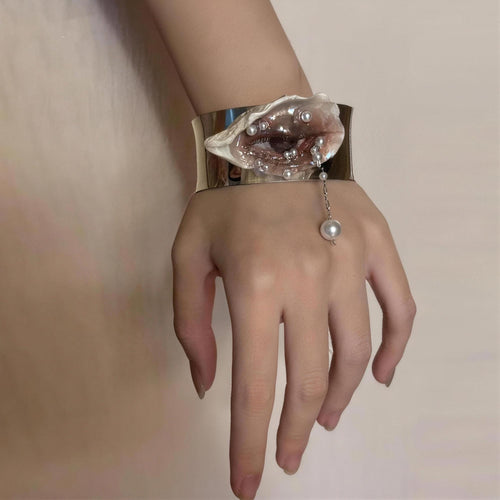 Gilded Oyster Eye Cuff Bracelet worn on a wrist beside pale fabric.